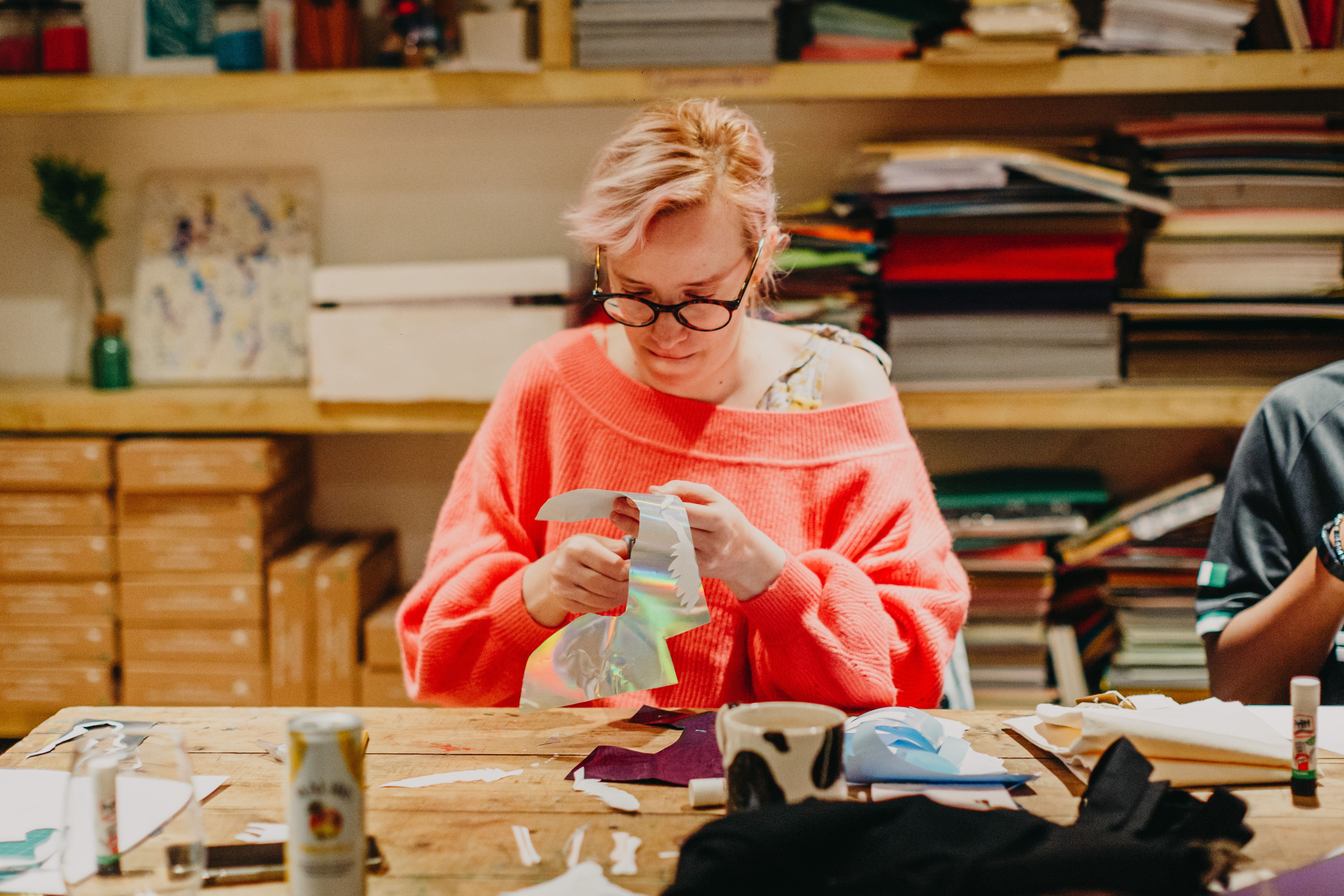 A person cutting up holographic paper at a sewing class